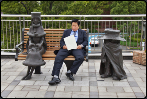 Mder Japaner zwischen den Statuen von Tetsuro and Maetel aus "Galaxy Express 999"